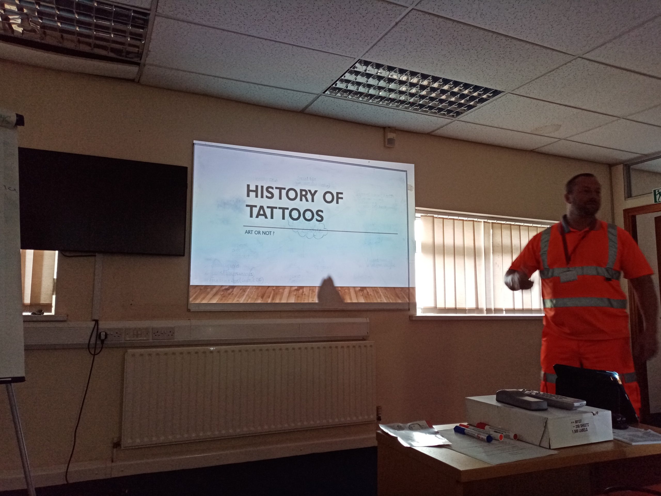 image of learner doing a presentation on the history of tattoos as part of Essential Skills qualification course.